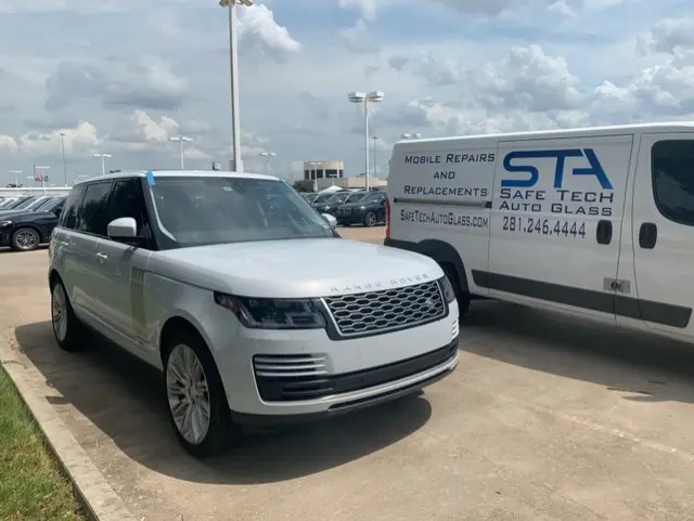 A white range rover parked in front of a white van.