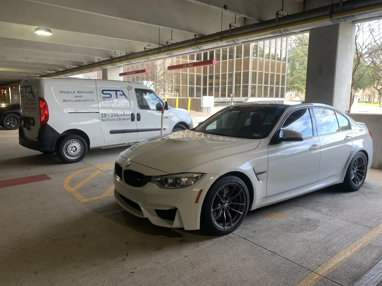 A white car parked in a parking garage next to a van.