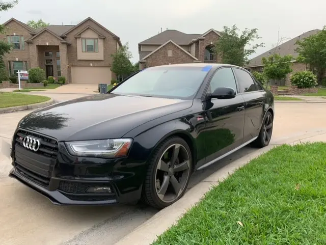 A black car parked in front of some houses